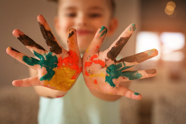 Hands covered in tempura paint. Focus is on hands.